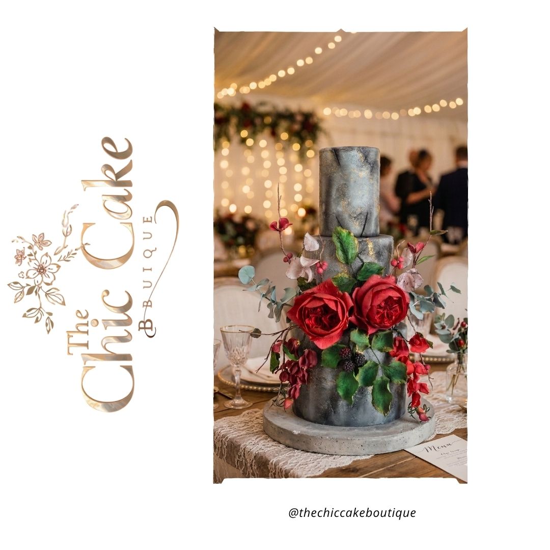Three tiered industrial stone effect wedding cake with textured grey and gold leaf fondant, decorated with dramatic red sugar roses and dark berries under warm marquee fairy lights. This alternative gothic style wedding cake with textured fondant designs made by the chic cake boutique serving Munster Irelamd